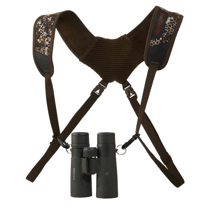 Badlands Bino Basic harness in camo and brown with ventilated shoulder straps and black binoculars attached.