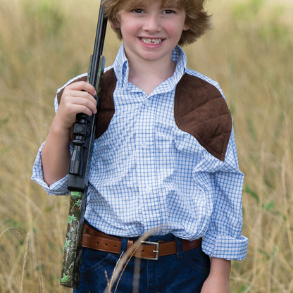 Young boy wearing a blue tattersall performance shooting shirt with brown quilted shoulder patches in a field.