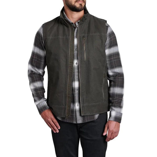 Kuhl Men's Burr olive cotton canvas vest with a zip-up chest pocket and fleece-lined interior over a plaid shirt.
