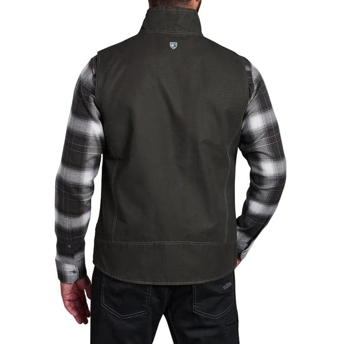 Back view of a dark olive Kuhl cotton canvas vest layered over a grey and black plaid flannel shirt.