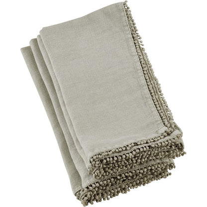 Folded beige linen-cotton blend napkin featuring a decorative pompom trim edge for a textured, elegant table setting.